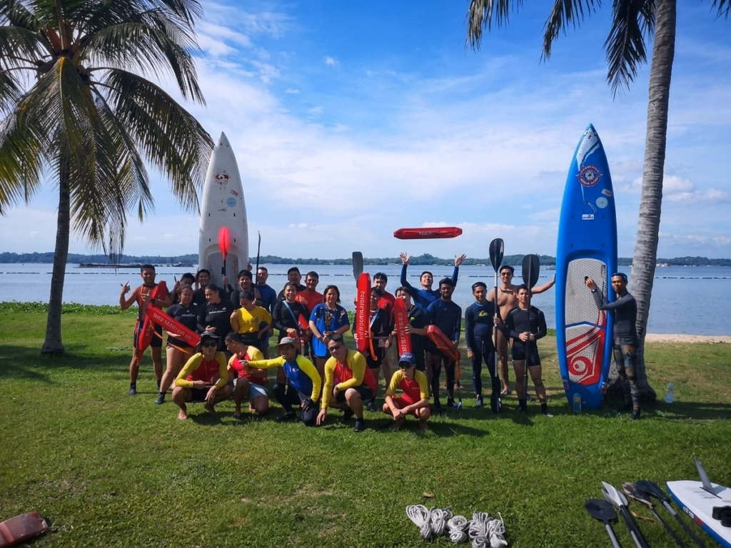 Lifesaving course participants with rescue tubes, paddles and paddleboards on the shore